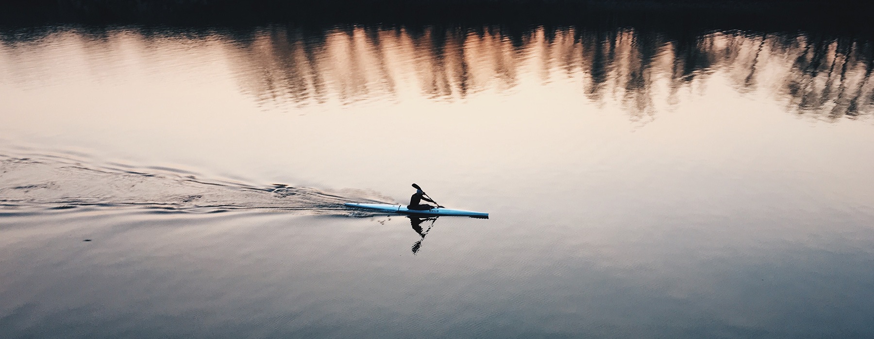 lifestyle image of a person rowing over reflective water